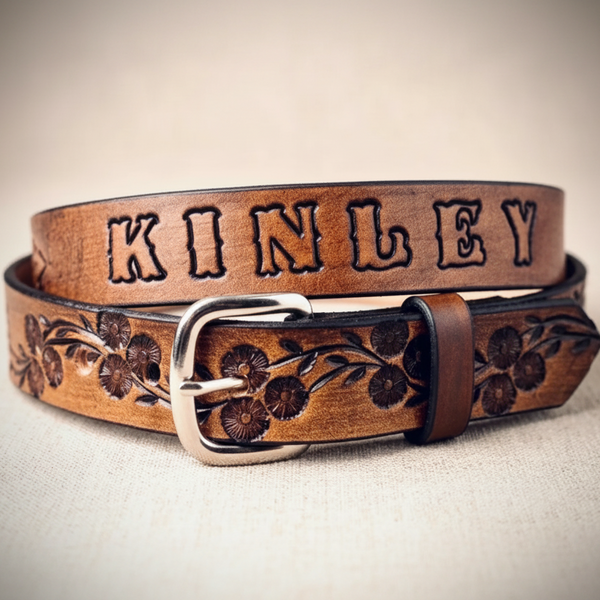 A brown leather belt with 'KINLEY' engraved in raised letters and floral tooling, shown coiled on a neutral background. The image is a screenshot of a product page with a sidebar and browser interface visible.