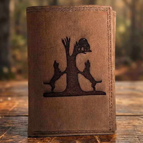 Distressed brown leather trifold wallet featuring an etched design of two dogs and a raccoon in a tree.